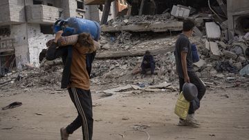 Palestinians walk through the destruction in the wake of an Israeli air and ground offensive in Khan Younis, southern Gaza Strip, Monday, April 8, 2024. Israel says it has withdrawn its last ground troops from the city, ending a four-month operation. 