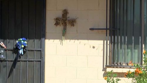 A cross crafted with dead flowers and other plant material is fastened to the outside of the dead boy's Arizona home.