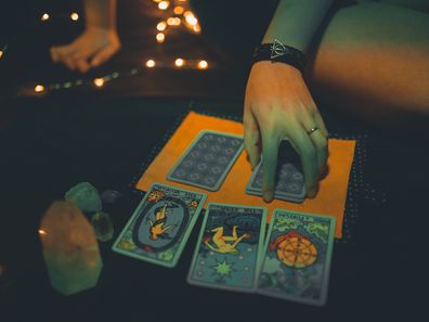 A woman deals tarot cards in the dark. Stock photo.