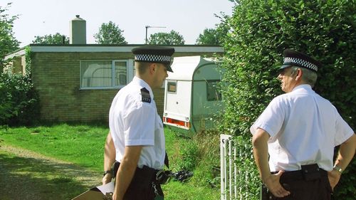 Police stand outside the Cambridgeshire home where Ian Huntley was arrested in 2002. (Photo: AP).