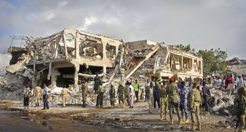 Somali security forces and others gather and search for bodies near destroyed buildings . (AP)
