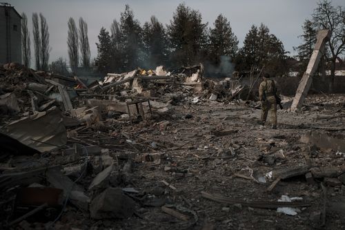 A volunteer of the Ukrainian Territorial Defence Forces walks on the debris of a car wash destroyed by a Russian bombing in Baryshivka, east of Kyiv, Ukraine, Friday, March 11, 2022