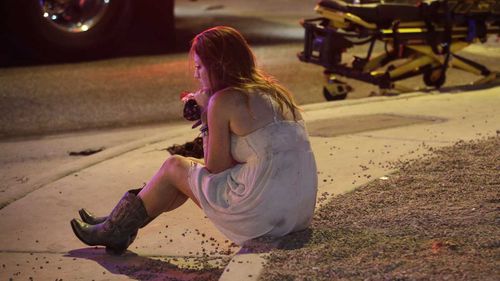 A survivor of the Las Vegas shooting sits alone on the kerb. (AAP)