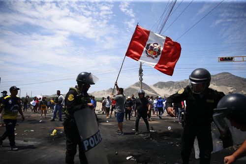 Des partisans du président péruvien évincé Pedro Castillo manifestent sur l'autoroute panaméricaine du Nord tandis que des policiers arrivent pour nettoyer les débris, à Chao, au Pérou, le jeudi 15 décembre 2022. 