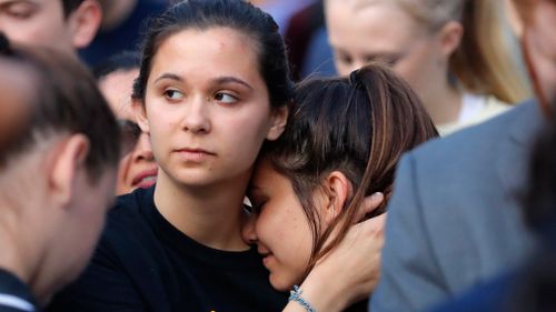 Survivors from Marjory Stoneman Douglas High School hug as they march to the state capitol to challenge lawmakers on gun control reform. (AAP)