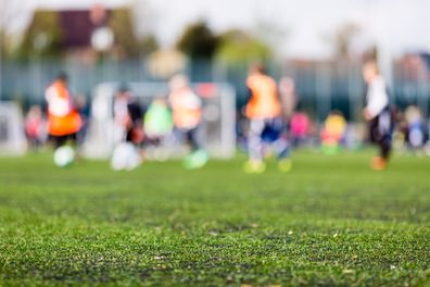 Shallow depth of field shot of young boys playing a kids soccer match on green turf.