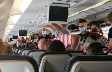 Passengers in face masks board a plane