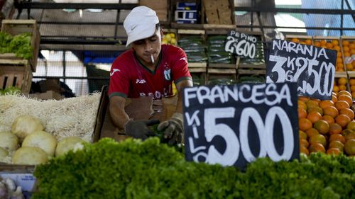 A vendor arranges vegetables at a market on the outskirts of Buenos Aires, Argentina