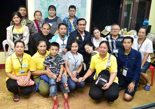 Thai Prime Minister Prayut Chan-o-cha  posies for a group photo with family members of a group of football players and their coach who have been trapped in a cave for two weeks. Picture: AP