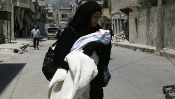 A woman carrying a baby in the streets of Manbij last week. (AFP)