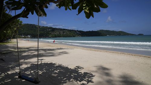 An empty swing hangs from a tree on the empty tourist beach of Patong on Phuket, southern Thailand.