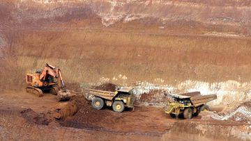 A digger and two heavy trucks on site at Mount Weld mine in Western Australia.  