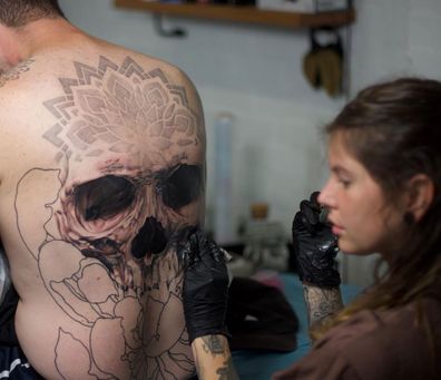 Jody Knight works on a huge back tattoo.