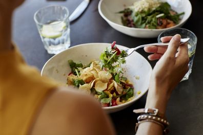 Cropped image of woman having food at restaurant table