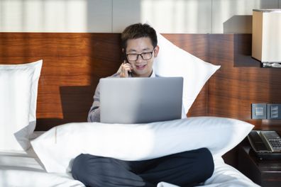 Employee typing on laptop in hotel bed