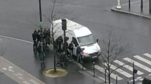 Police huddle behind a van in east Paris where another hostage situation is unfolding.