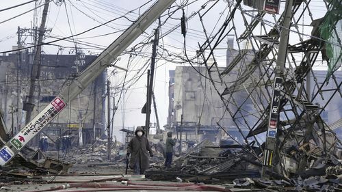 People walk through the damaged marketplace burnt by fire after earthquake in Wajima, Ishikawa prefecture, Japan on Tuesday.
