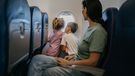 Mother with two children, son and daughter  traveling by plane, kids are looking through window