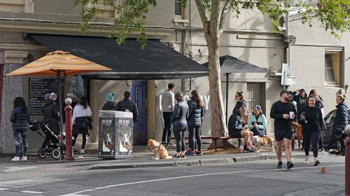 People practice social distancing as they wait for their coffee at a cafe in Richmond.