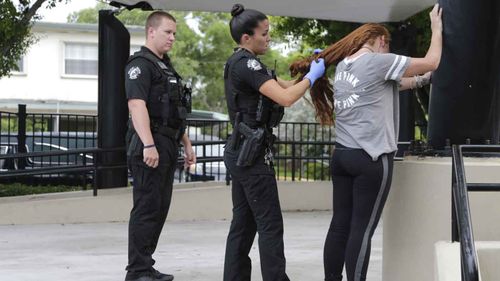 Officer Stephanie Holst, searches a woman for suspected drug paraphernalia at a city park in Delray Beach. (AP)