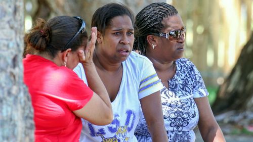 Three women, believed to be relatives of the victims, near the scene of the crime. (AAP)