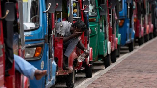 An autorickshaw driver washes his face as he waits in a queue hoping to get fuel near a fuel station in Colombo, Sri Lanka.