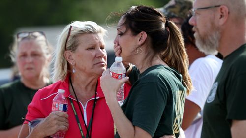 Santa Fe High School staff react as they gather in the parking lot of a gas station. Picture: AP