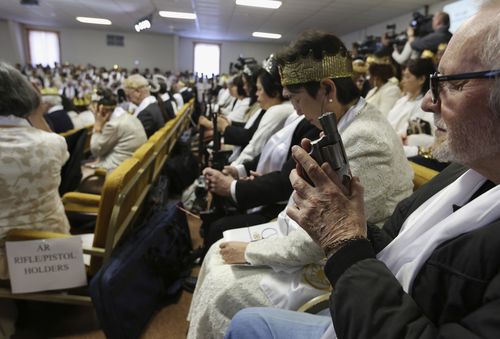 The members hold tightly on to their guns during prayer. (AAP)