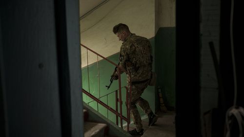 A Ukrainian serviceman walks inside a building after searching the apartment of a man suspected of being a Russian collaborator in Kharkiv, Ukraine.