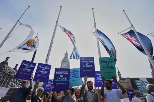 Demonstrators for assisted dying hold banners outside Parliament in London, Friday, June 20, 2025