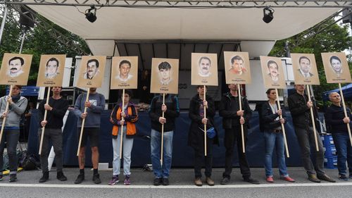 People hold banners with portraits of murdered migrants in front of the Higher Regional Court in Munich, Bavaria, Germany.