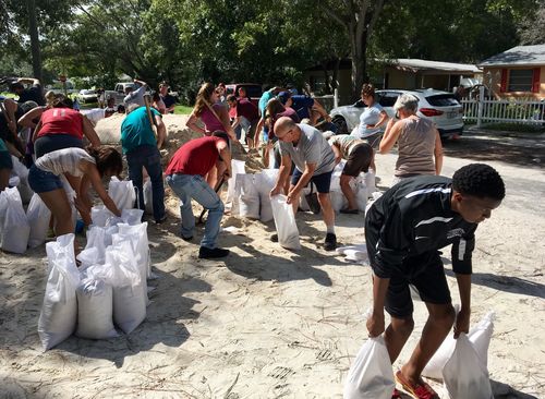 Joseph, Jr., right, 15, of St. Petersburg, bends down to carry sandbags to his family's vehicle at Lealman Community Park in Florida. (AP)