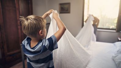 Little boys aged 8 are making bed together.