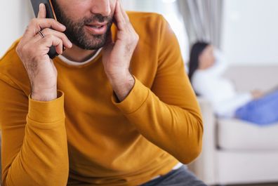 Man talking on the phone while woman sits behind him