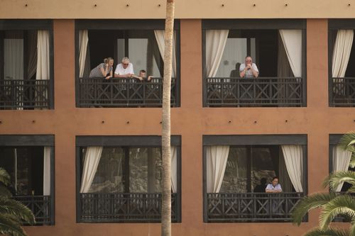 People stand on their balconies of the H10 Costa Adeje Palace after the hotel went into lockdown following two guests testing positive for coronavirus.