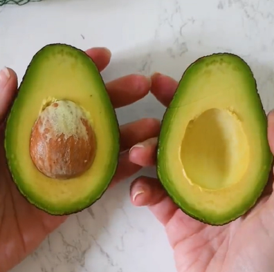 Perfectly ripe avocado cut in half held in hands