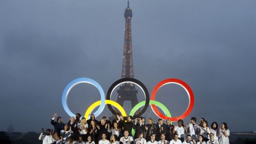 Paris officials pose in front of a display showing the Olympic rings on Trocadero plaza that overlooks the Eiffel Tower, as they celebrate the vote in Lima, Peru. (AAP)