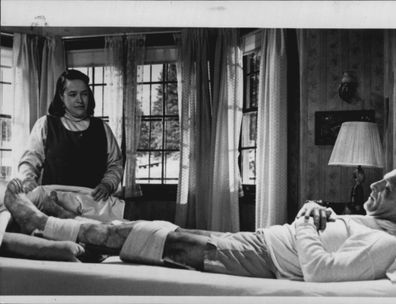 Nurse Annie Wilkes (Kathy Bates) tends to novelist Paul Sheldon (James Caan), after a horrific accident leaves both his legs broken, in "Misery". 