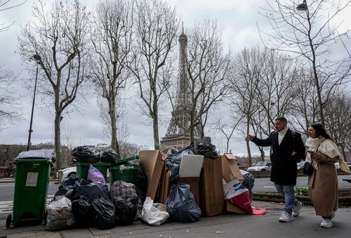 People walk past not collected garbage cans near the Eiffel Tower in Paris.