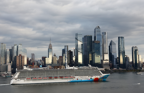 A shot of a cruise ship along the Hudson River in front of Hudson Yards and the Empire State Building in New York