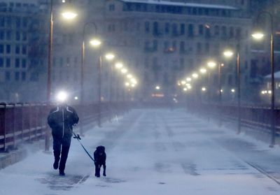 A runner and his dog brave frigid conditions while making their way east across the Stone Arch Bridge in Minneapolis.