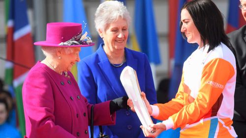 The Queen hands over the baton to cyclist Anna Meares. (AAP)