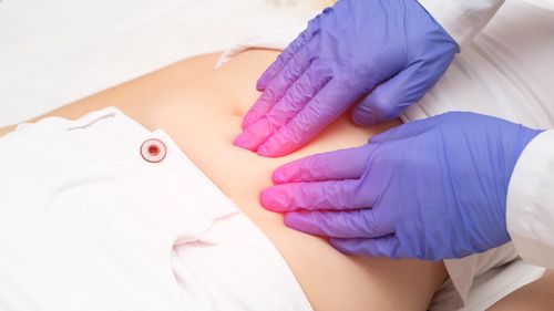 A gynecologist doctor probes the lower abdomen of a girl who has pain and inflammation of the reproductive system. Ovarian cyst