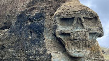Mystery surrounds the appearance of a stylised skull carved into the sandstone cliffs at Waipipi Beach in New Zealand.
