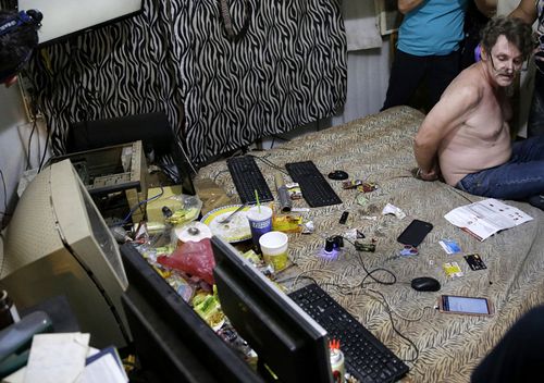 David Timothy Deakin, from the US, with his hands tied behind his back during a raid by investigators, sits on his bed where he handles online sharing of videos of children engaging in sexual acts in Mabalacat, Philippines. (AAP)