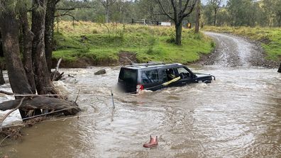 Three people rescued by police officer from car stuck in floodwaters in NSW Hunter region.