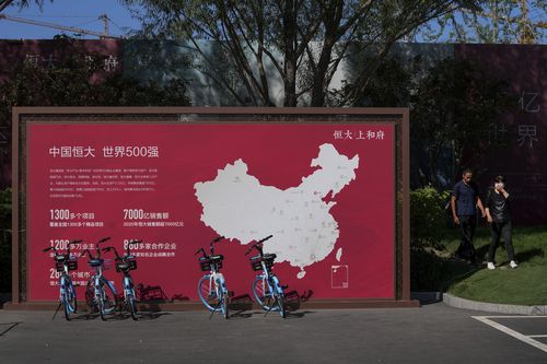 People walk by a map showing Evergrande development projects in China at an Evergrande new housing development in Beijing in September.