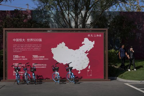 La gente passa davanti a una mappa che mostra i progetti di sviluppo di Evergrande in Cina al nuovo progetto residenziale Evergrande a Pechino a settembre.