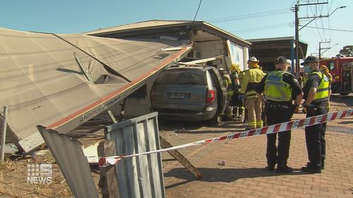 Police officers survey the damage after the roof of the building collapsed onto the vehicle.