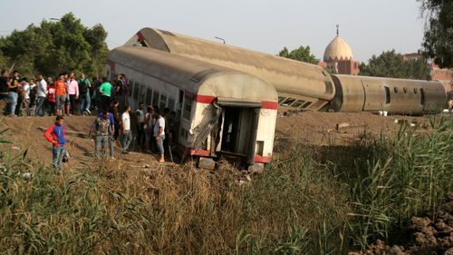 People gather at the site where train carriages derailed in Qalioubia province, north of Cairo.